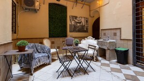 A cozy outdoor seating area with a table, chairs, and a potted plant. - Domus Luxury Suite  (Rome)