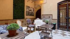 A cozy outdoor seating area with a checkered floor, a potted plant, and a white chair. - Domus Luxury Suite  (Rome)
