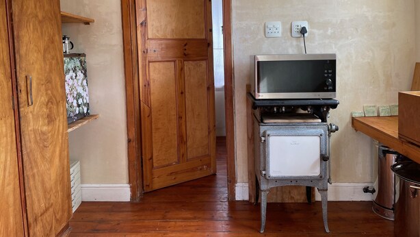Una stanza con un armadio in legno, un televisore vintage su un tavolino e una porta che dà su un'altra stanza.