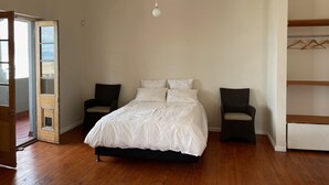 A bedroom with a bed, two chairs, a wardrobe, and a hanging light fixture. - Studio apartment in the heart of Kalk Bay,  1 minute walk to the beach. (Cape Town)