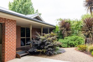 Guests can enjoy a porch with a large window overlooking a beautifully maintained garden.