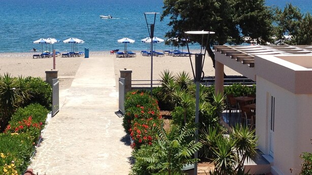 A beachside hotel with a pathway leading to the beach, umbrellas, and a view of the sea. - Amaryllis Front Beach Hotel (Rhodes)