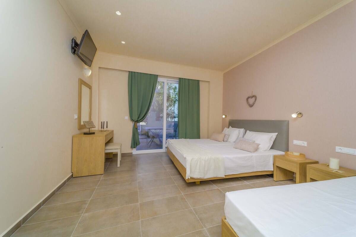 A bedroom with a bed, a desk, a chair, and a TV mounted on the wall.