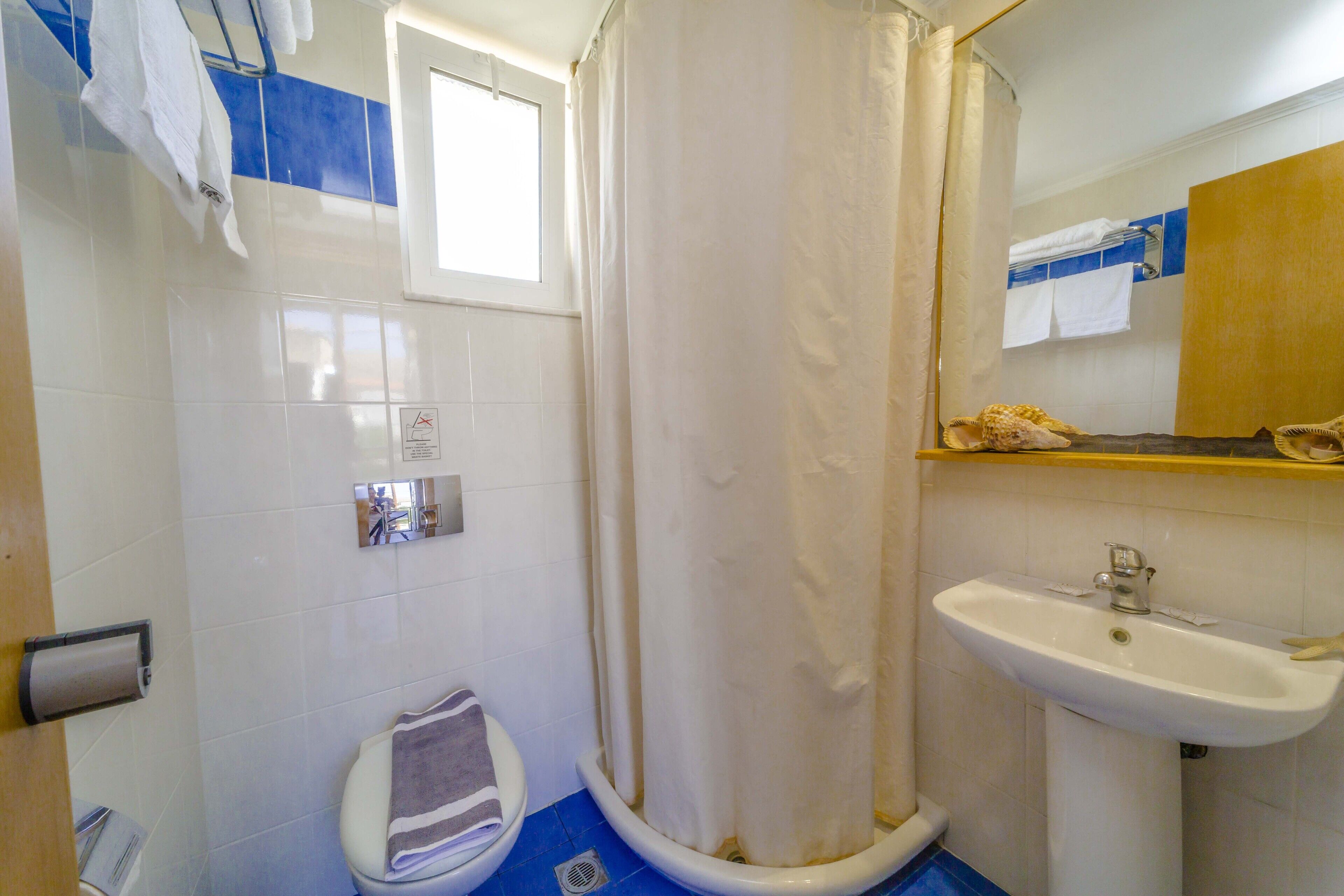 Une salle de bain équipée d’une douche, de toilettes, d’un lavabo et d’un porte-serviettes.