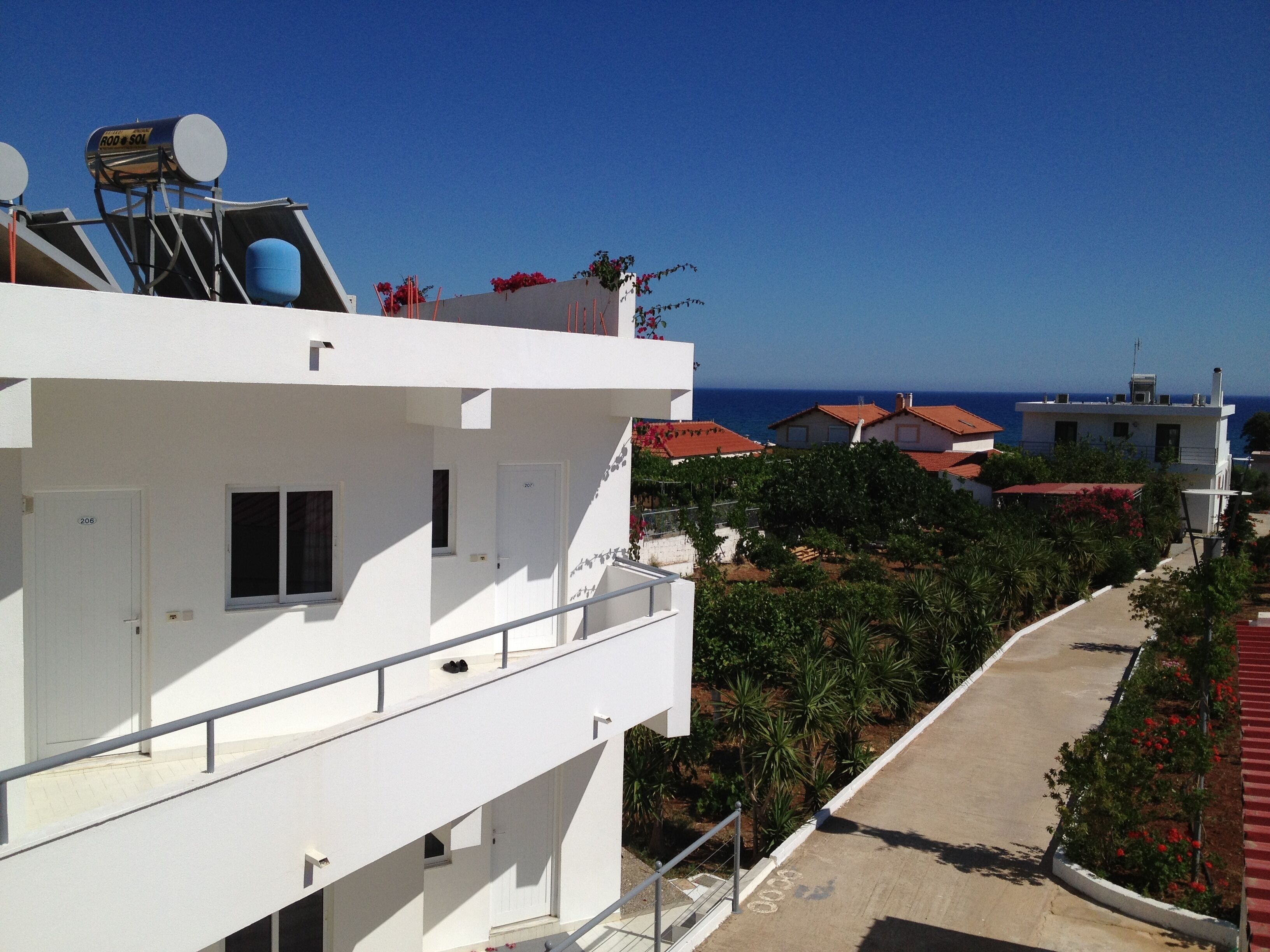 Un edificio blanco con un balcón, una antena parabólica y vistas al mar.