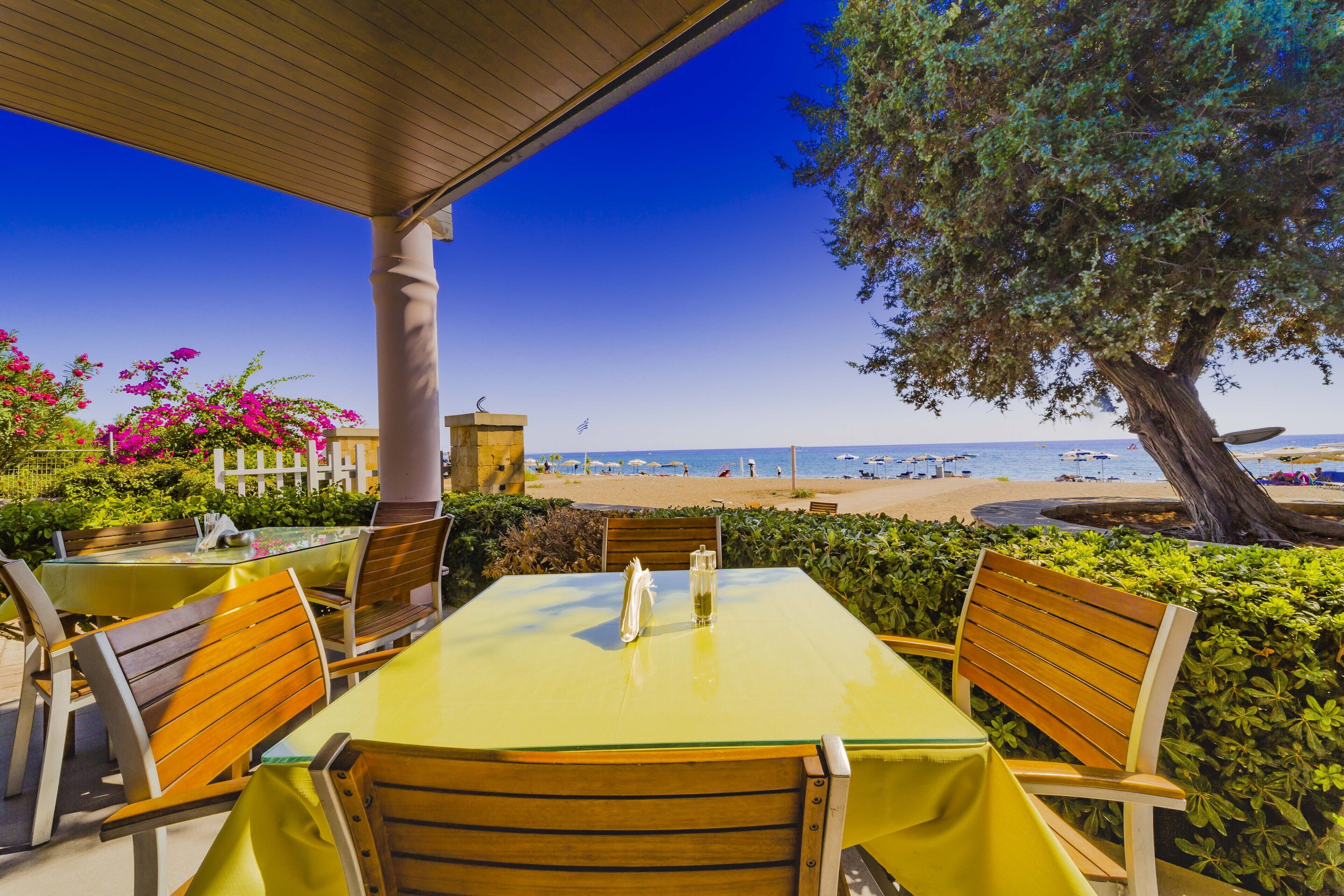 Un espacio de comedor al aire libre con vista a la playa y al océano.