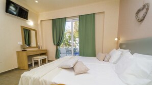 A hotel room with a bed, a desk, a chair, a TV, and a view of the outdoors. - Amaryllis Front Beach Hotel (Rhodes)
