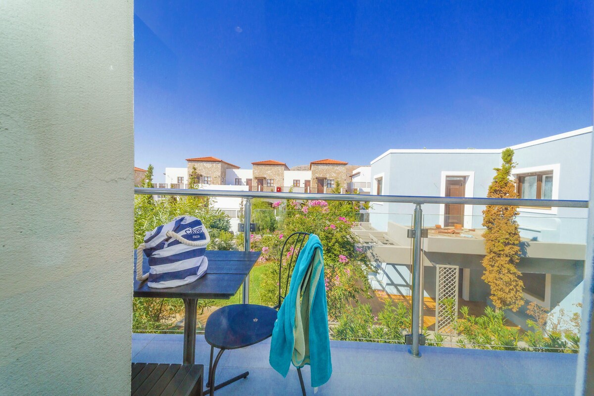 A balcony with a table, a chair, a bag, and a hanging towel.