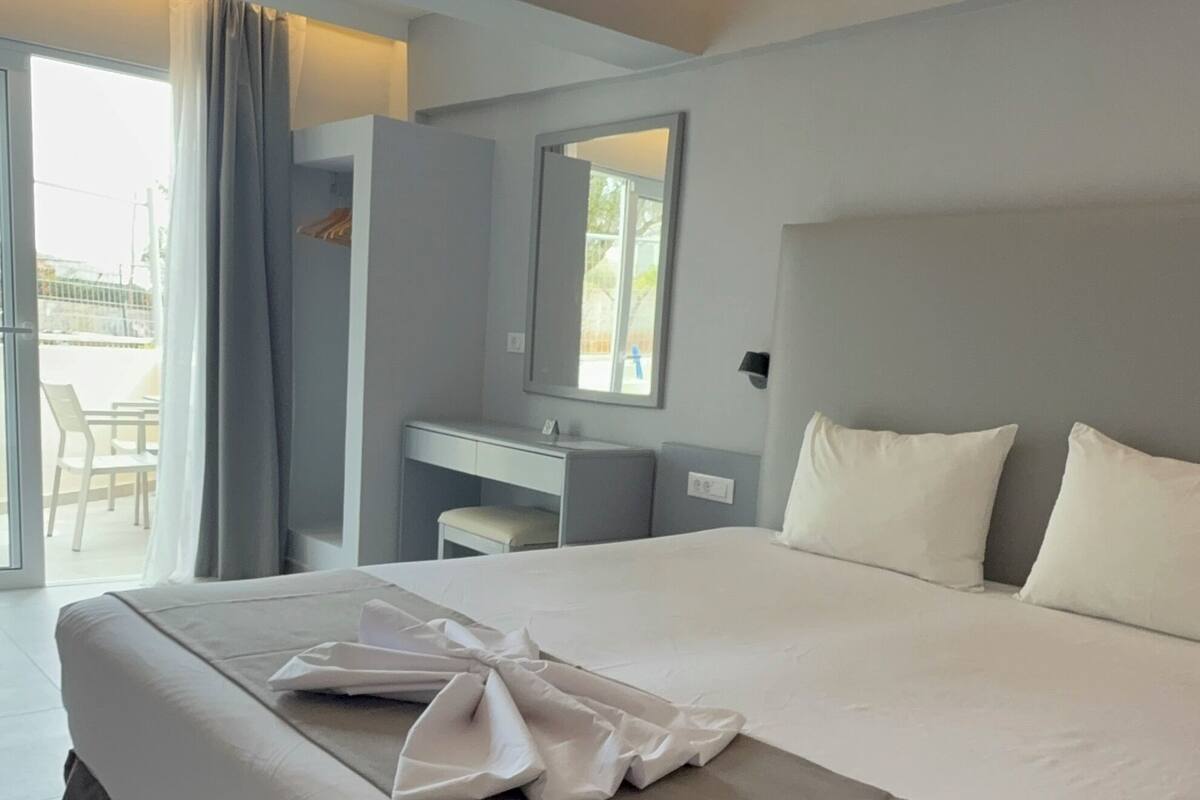 A modern hotel room with a large bed, a desk, and a balcony.