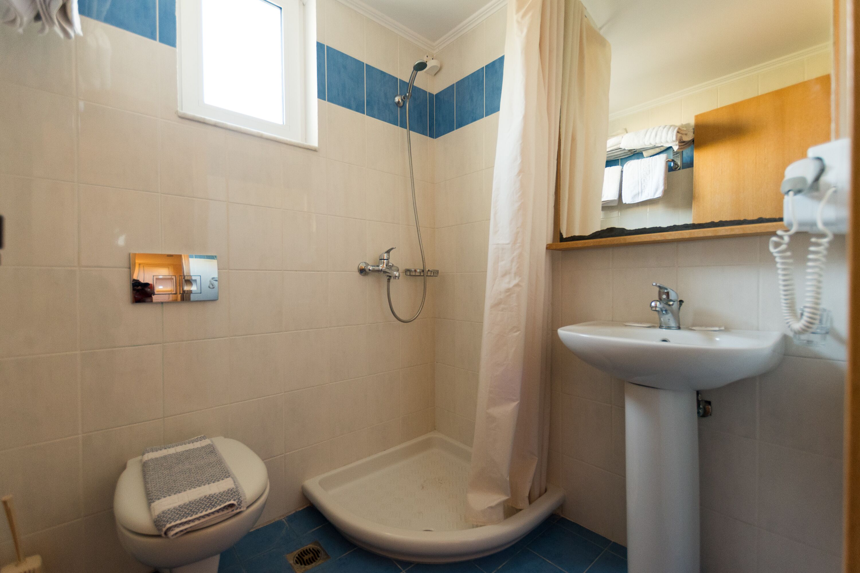 Een badkamer met douche, toilet en wastafel.
