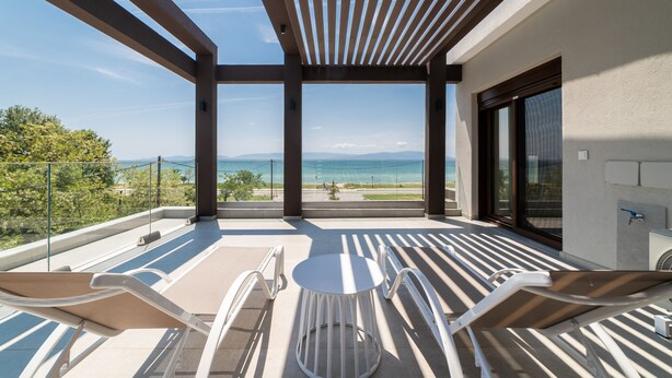 Un balcón con vista al mar, una mesa y dos sillas.
