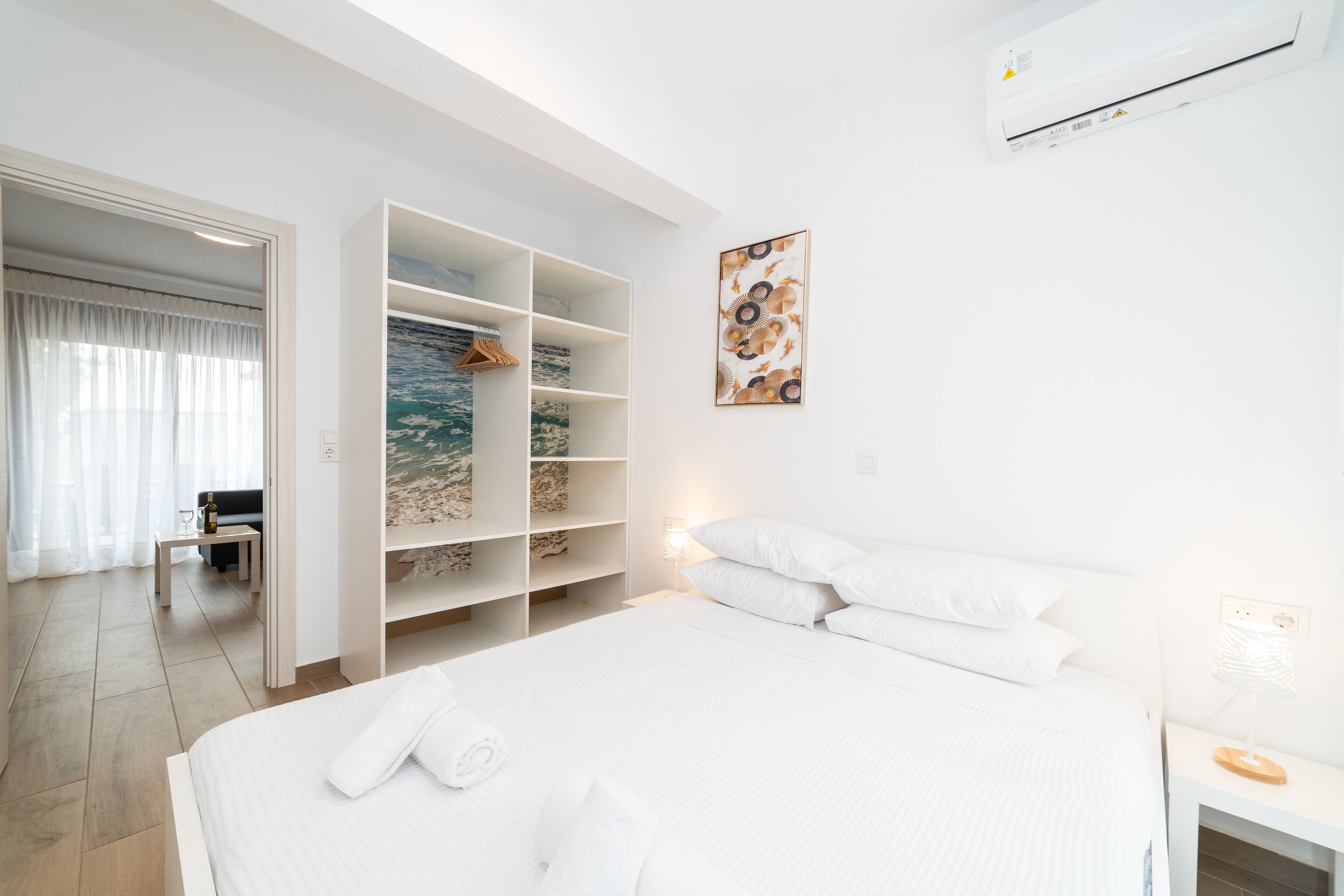 Ett modernt hotellrum med en stor säng, en inbyggd garderob och utsikt över havet genom ett stort fönster.