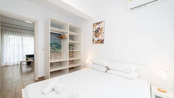 Ett modernt hotellrum med en stor säng, en inbyggd garderob och utsikt över havet genom ett stort fönster.