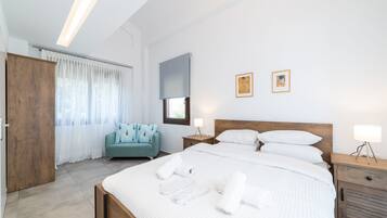 Un dormitorio moderno con una cama grande, un armario de madera, un sofá color turquesa y dos mesitas de noche con lámparas.