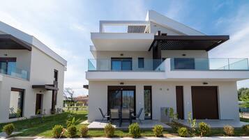 Una casa moderna de dos pisos con balcón, garaje y césped bien cuidado.
