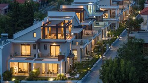 Una zona residencial moderna con casas contemporáneas que incluyen balcones, ventanas amplias y espacios exteriores bien iluminados.