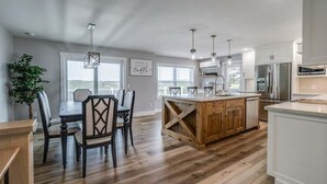 Una cocina amplia con una isla central, armarios de madera y una zona de comedor con mesa y sillas.