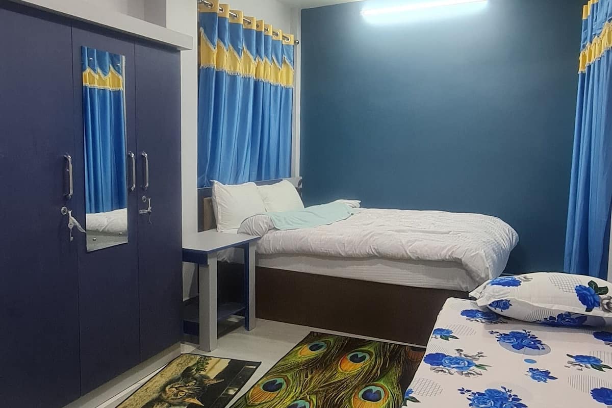 A bedroom with a bed, a desk, a wardrobe, and curtains.