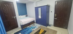 A bedroom with a bed, a wardrobe, and two doors. - Hotel Homestay Inn (Madhyapur Thimi)