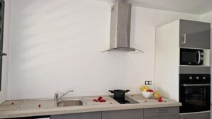 Una cucina moderna con lavello in acciaio inossidabile, cappa aspirante, forno a microonde e forno.