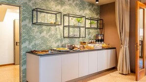 Un área de buffet con un mostrador, estantes con plantas y una variedad de alimentos.