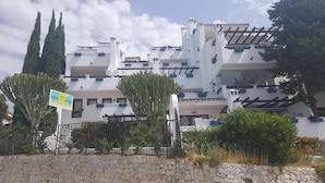 Un bâtiment moderne doté de nombreux balcons et d’un mur en pierre à l’avant.