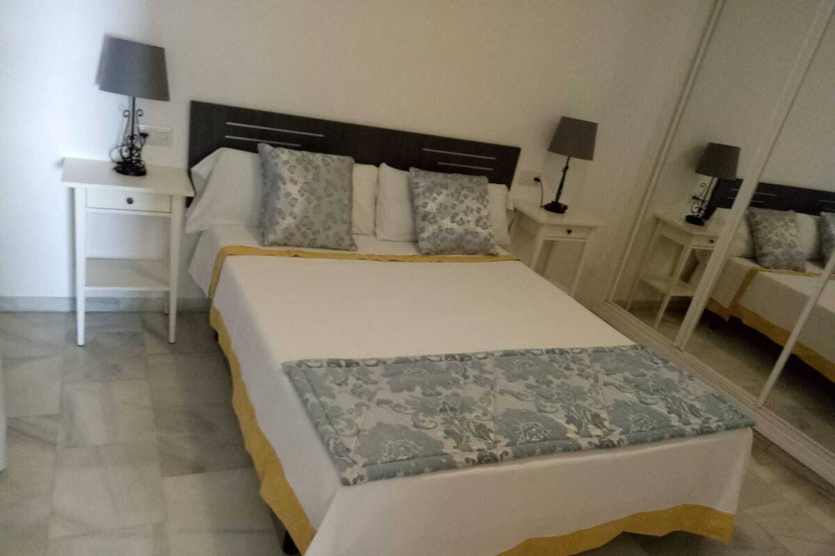 A neatly arranged bedroom with a large bed, two bedside tables, and a mirror.