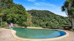A clear swimming pool with a curved edge, surrounded by a stone patio. - Molla Eco Lodge Kangaroo Valley (Wattamolla)
