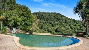 Relax by the serene pool surrounded by lush greenery and forested hills.