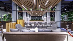 A modern lounge area with a sofa, bar stools, and a central seating area with a table. - Mabaat - Al Malqa - 523 (Riyadh)
