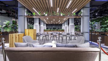 A modern lounge area with a sofa, bar stools, and a central seating area with a table.