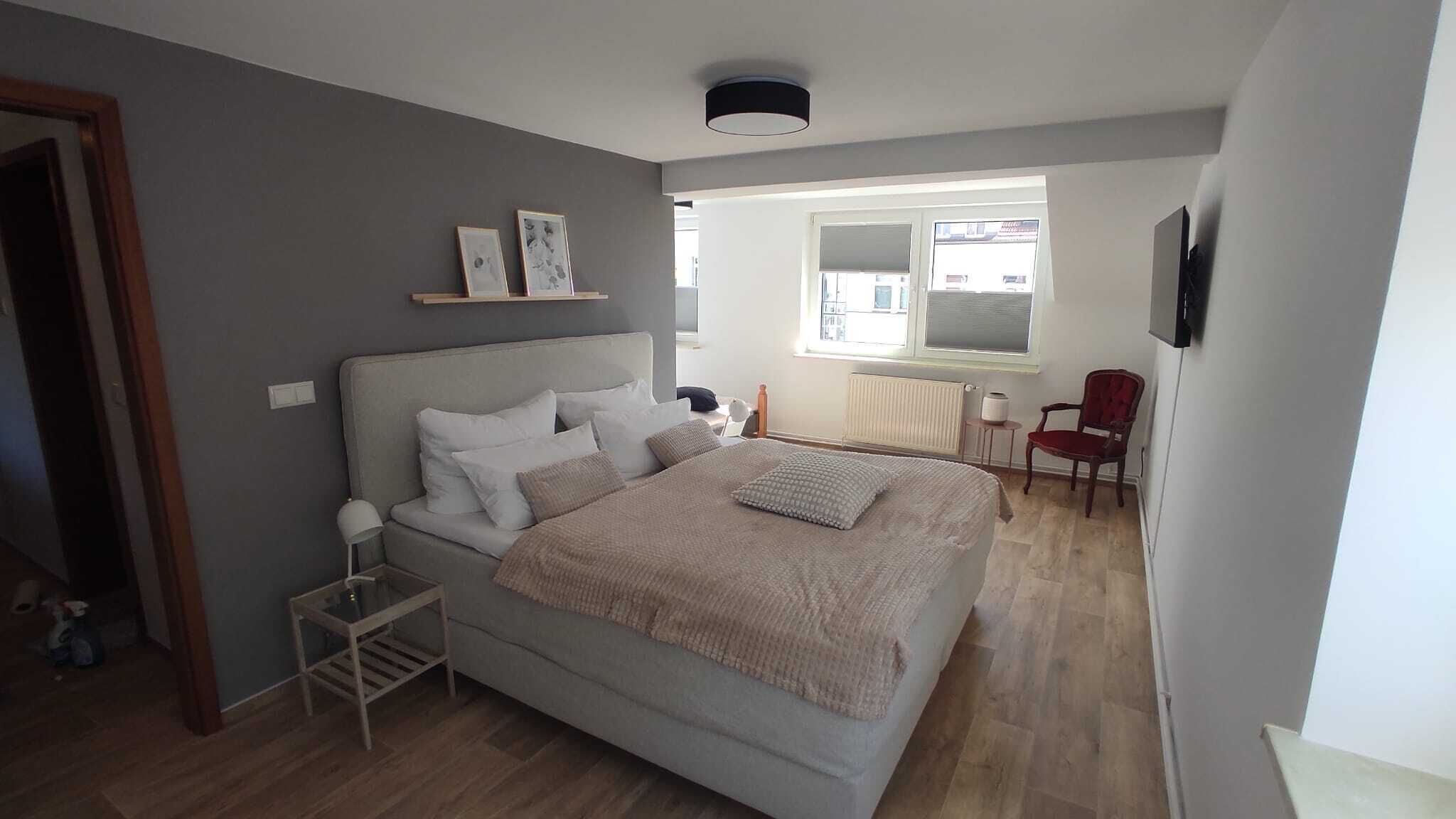 A bedroom with a bed, bedside table, and a chair.