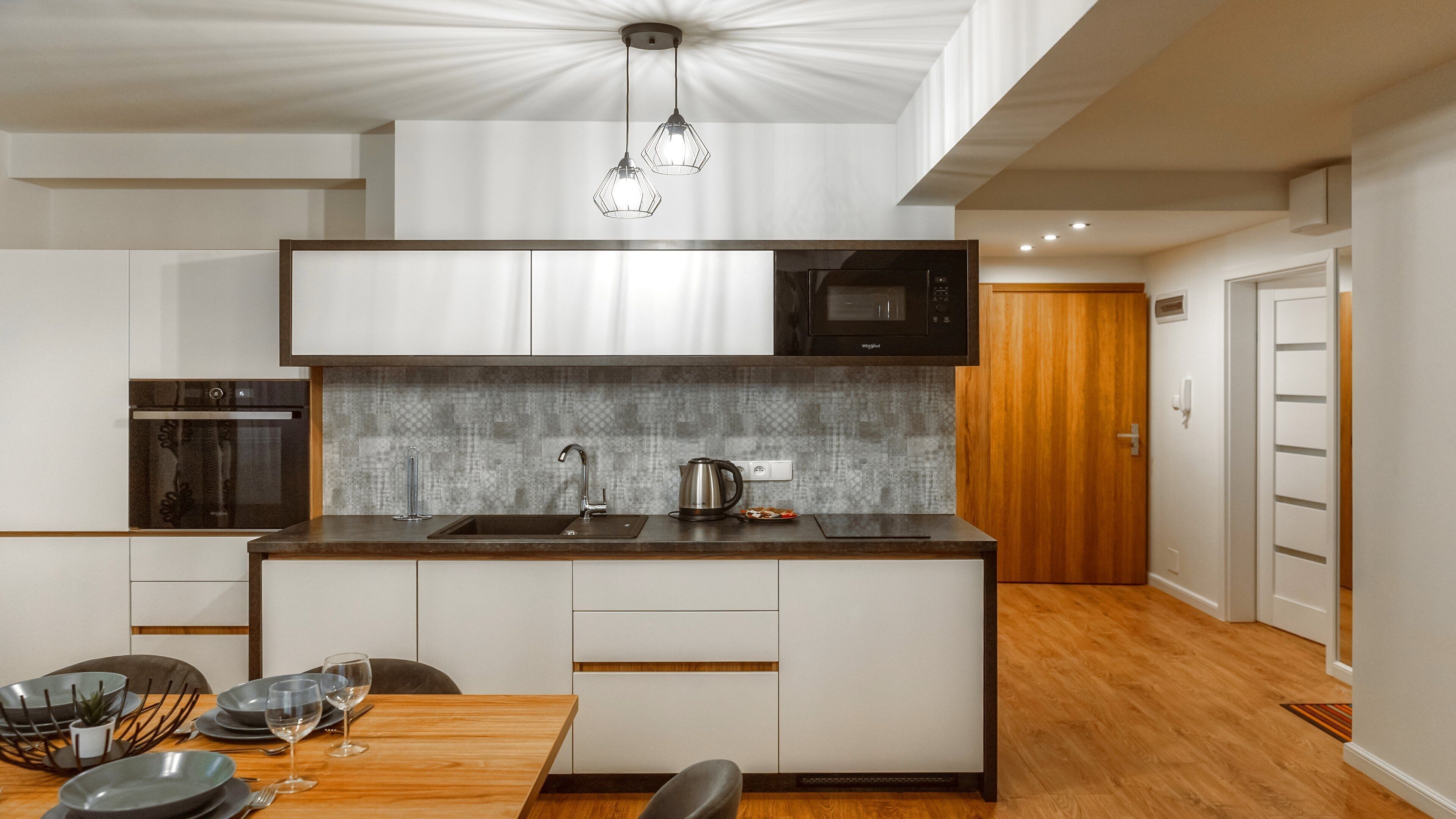 Cozinha moderna com ilha central, eletrodomésticos de aço inoxidável e painel de fundo padronizado.