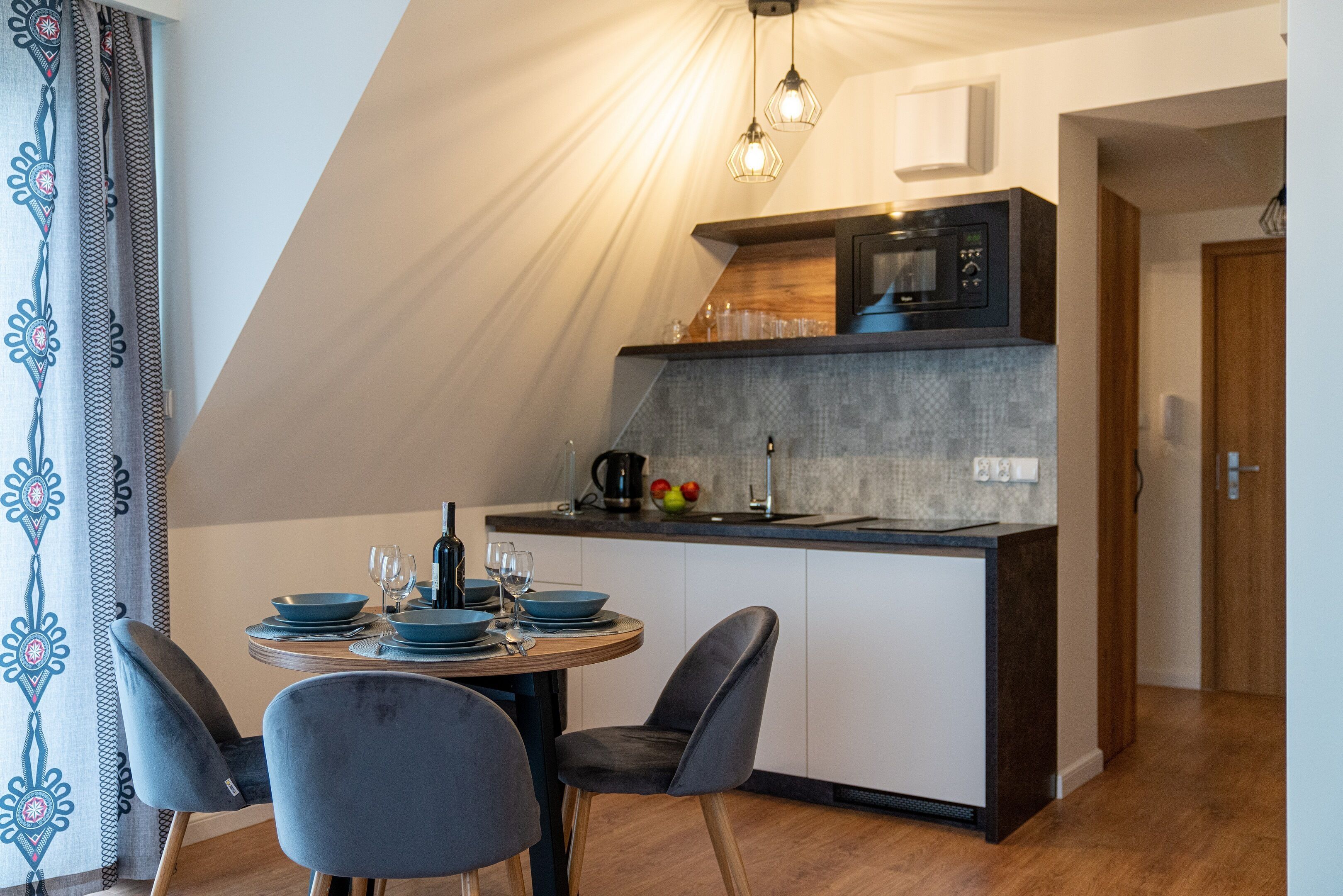 A modern kitchen with a dining area, featuring a round table, chairs, and a microwave.
