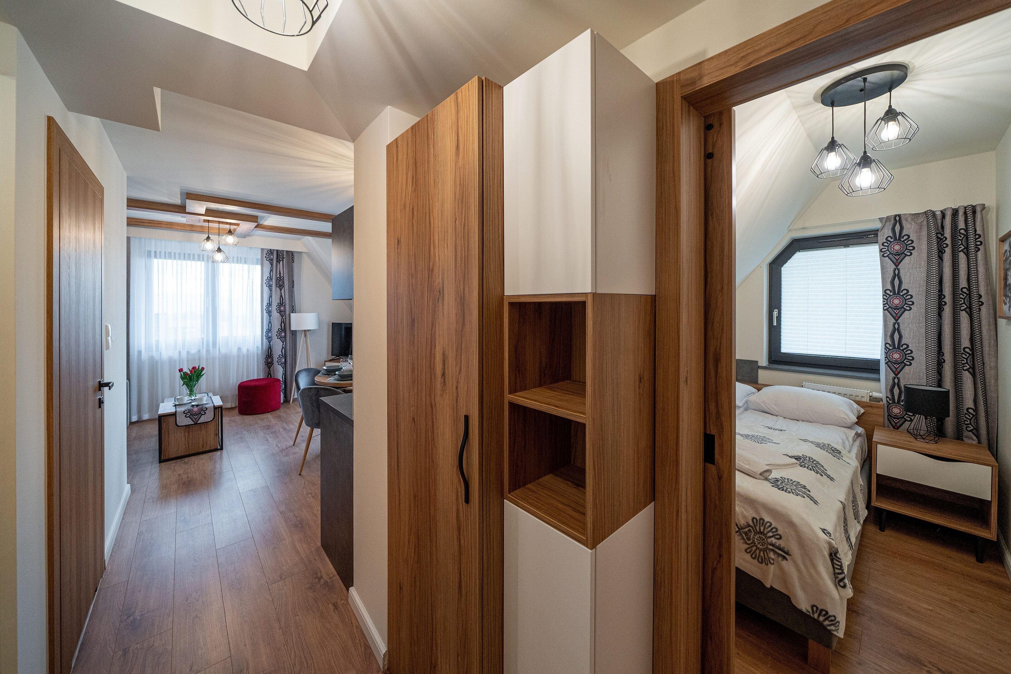 A modern bedroom with a bed, bedside table, and a window with curtains.