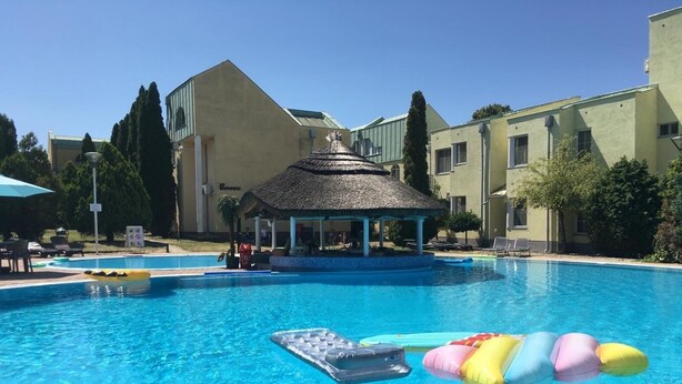 Una piscina con sillones de descanso y un pabellón.