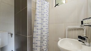 Un baño con un lavamanos blanco, una cortina de ducha con estampado de peces y un toallero.