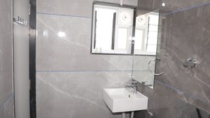 A modern bathroom with a white sink, a glass shower enclosure, and a large mirror. - VITS SelectSasangir (Talala)