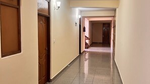 A hallway with a wooden door, a light fixture, and a tiled floor.