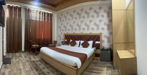 A hotel room with a wooden bed, a nightstand, a chair, and a desk.