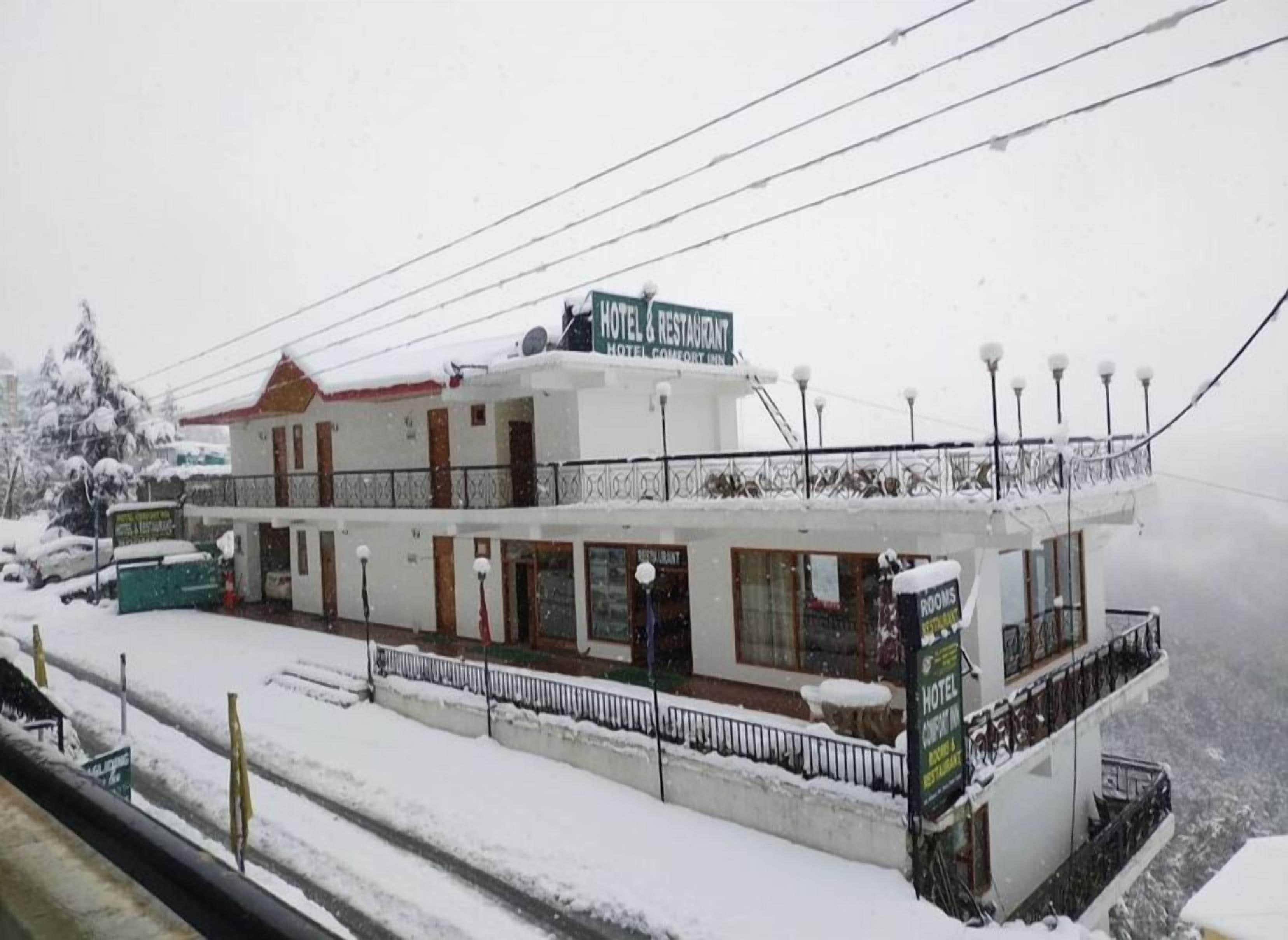 A two-story hotel with a sign indicating it offers rooms, a restaurant, and a cafe.