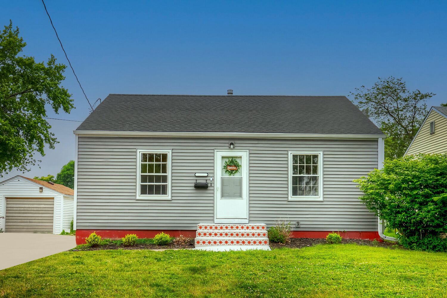 A two-story house with a front porch, a garage, and a well-maintained lawn.