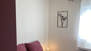 A bedroom with a bed, pillows, a bedside table with a lamp, and a wall art piece. - La Campagne Proche de Paris - Chez Marie-louise (Montreuil)