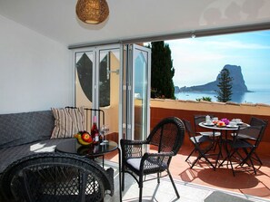 A balcony with a sofa, chairs, a table, and a view of the sea and a mountain. - Cosy apartment for 4 guests with WIFI, A/C, TV and terrace (Calpe)