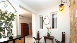 Une pièce avec un meuble en bois, des paniers en osier, une petite table sur laquelle est posée une plante en pot et un luminaire suspendu.
