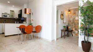 Une cuisine moderne avec des meubles blancs, un îlot central et un coin repas doté de chaises en bois.