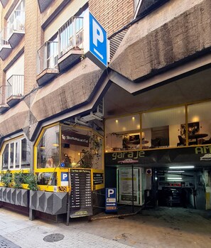 A building with a parking garage entrance and a restaurant named 'La Hummuseria' on the ground floor. - Great Loft with Terrace in Madrid heart (Las Rozas de Madrid)
