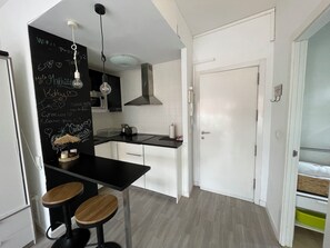 A modern kitchen with white cabinets, a black countertop, and two wooden stools.