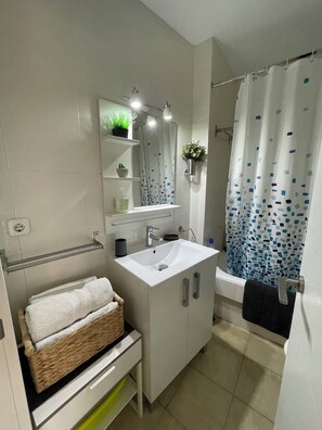 A modern bathroom with a white sink, mirror, and shower curtain.