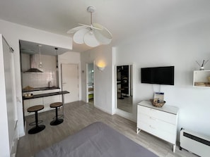 Une chambre moderne et bien Ă©clairĂ©e, Ă©quipĂ©e dâun lit, dâune tĂ©lĂ©vision, dâun bureau et dâun coin cuisine.